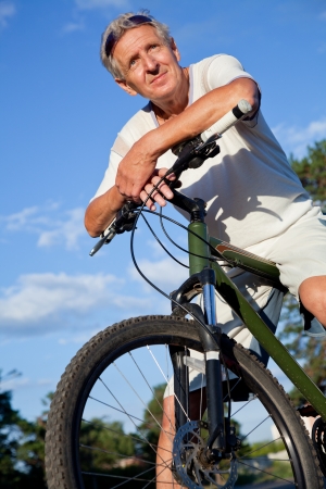 happy senior man cycling in the summer parkの写真素材