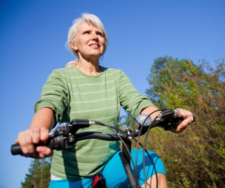 happy senior woman cycling in the summer parkの写真素材
