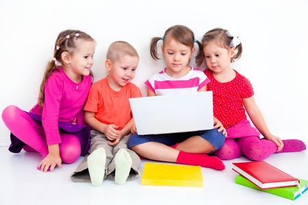 Group of four children working on laptop together 
