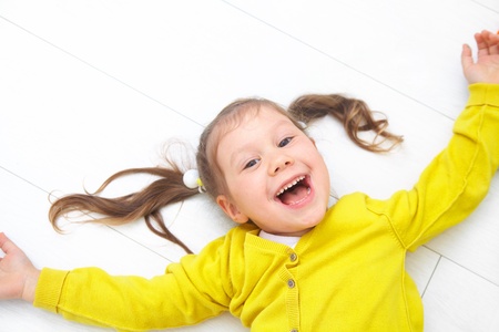 Portrait of funny little girl lying on floorの写真素材