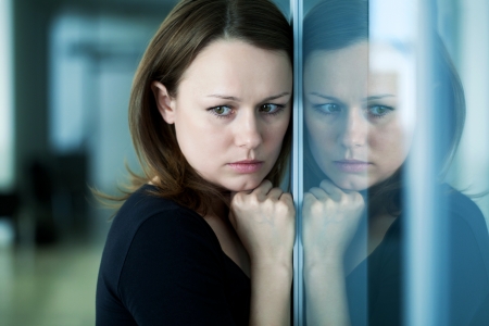 young woman  woman leaned against glass wall in crisis moment の写真素材