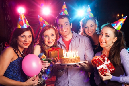 young company holds a cake with candles on birthdayの写真素材