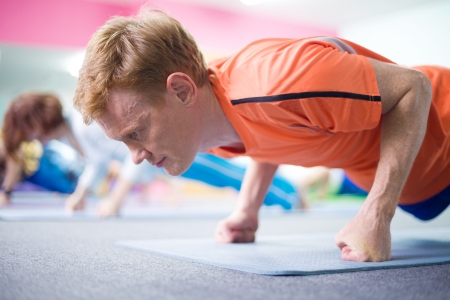 Portrait of young man doing yoga with other people in background の写真素材