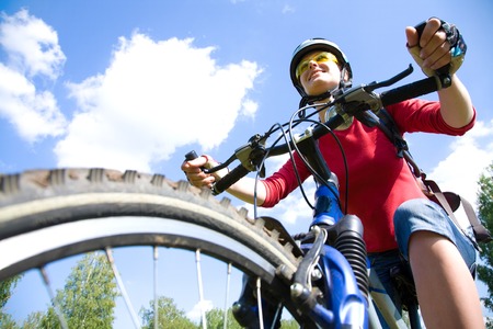 Young cyclist on a mountain bike and the blue sky in the parkの写真素材