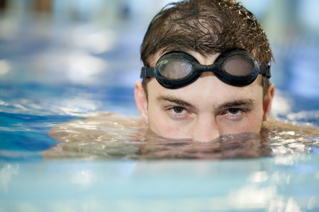 Happy attractive man swimming in blue water in  swimming poolの写真素材