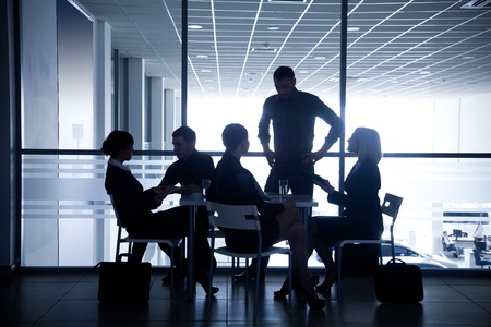 Several silhouettes of businesspeople interacting  background business centreの写真素材