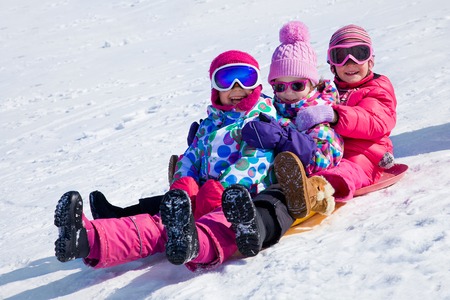 group of kids riding on snow slides in winter timeの写真素材