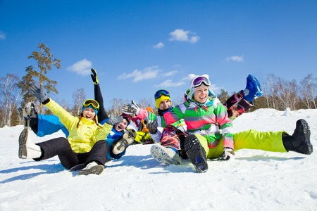 group of funny friends slide downhill together on mountain holidayの写真素材