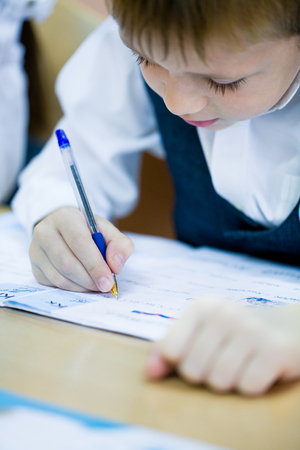 schoolboywrites in a notebook at schoolの写真素材