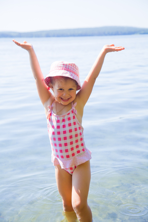 Happy little girl having fun, swimming  at shallow waterの写真素材