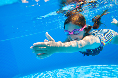 little girl deftly swim underwater in poolの写真素材