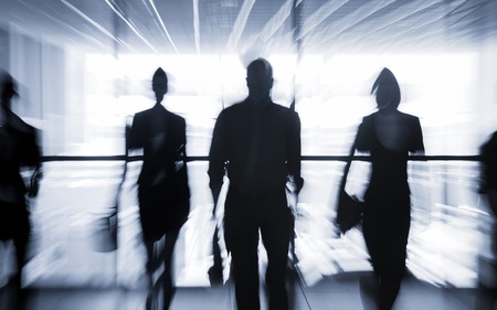 Several silhouettes of businesspeople interacting office backgroundの写真素材