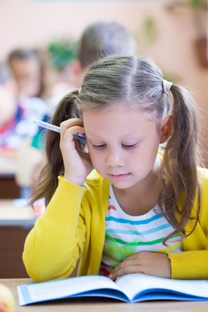 schoolgirl sits at a school desk at a lesson at schoolの写真素材