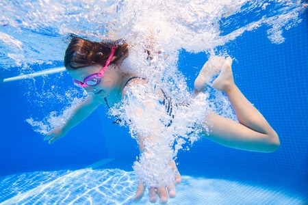 Cheerful little girl playing under  water in pool.の写真素材