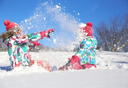 two little girls playing  on snow in winter timeの写真素材