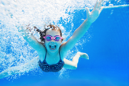 little girl creates bubbles under water in the poolの写真素材
