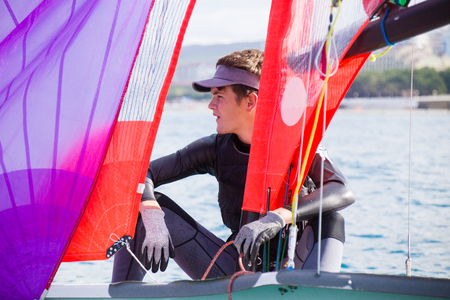 young guy drives a sailing yacht on the seaの写真素材
