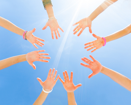 hands of young people stretching to the center on beachの写真素材