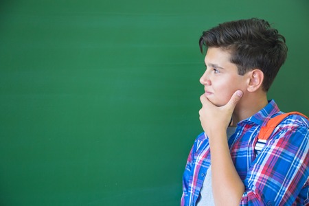 teenager student thinks at the blackboard