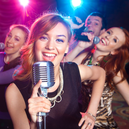 Young girl singing into  microphone at  partyの写真素材