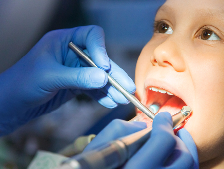 little girl is treating teeth with a pediatric dentistの写真素材
