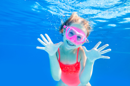 Cheerful little girl playing under  water in pool. Underwater photo.の写真素材