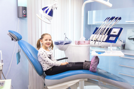 Little girl sitting in a chair near a dentist after dental treatmentの写真素材
