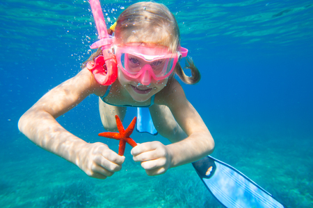 portrait of a little girl diving the sea for a starfishの写真素材