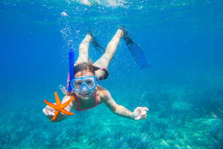 portrait of a little girl diving the sea for a starfishの写真素材