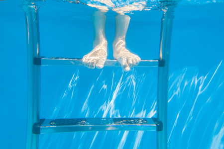  feet of kid under water in a swimming poolの写真素材