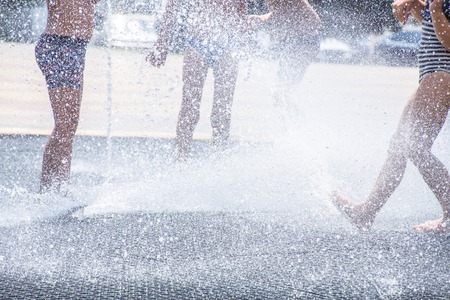 children play with splashes in the street fountainの写真素材
