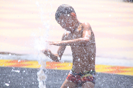 children play with splashes in the street fountainの写真素材