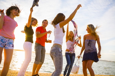 group of happy young people dancing at the beach on  beautiful summer sunsetの写真素材