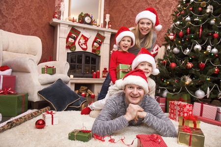 happy family celebrating Christmas near the fireplace under the Christmas treeの写真素材