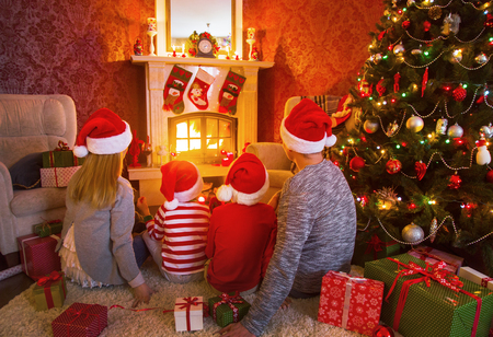 happy family celebrating Christmas near the fireplace under the Christmas treeの写真素材