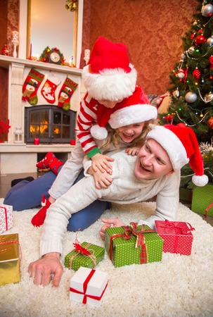 happy family celebrating Christmas near the fireplace under the Christmas tree. Father with children.の写真素材