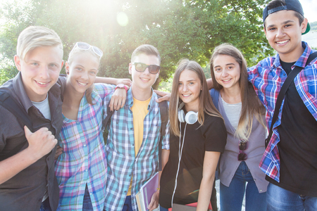 group of teenagers with textbooks and gadgets on background of green parkの写真素材