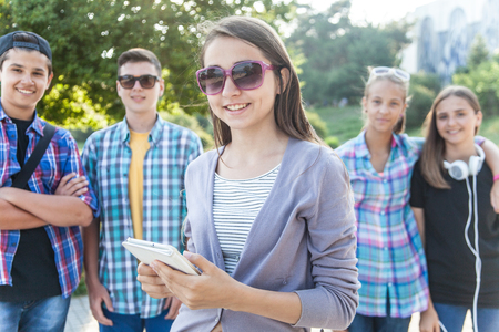 group of teenagers with textbooks and gadgets on background of green parkの写真素材