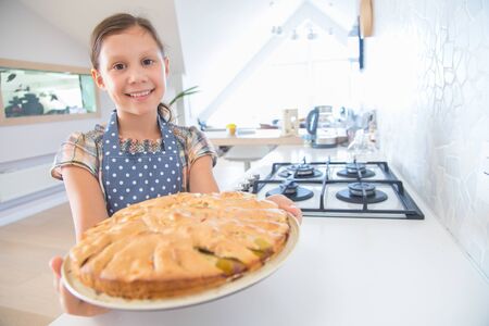 little girl herself cooked charlok in the oven in the kitchen of the houseの写真素材