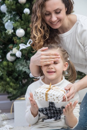 Mother surprising her daughter with christmas giftの写真素材