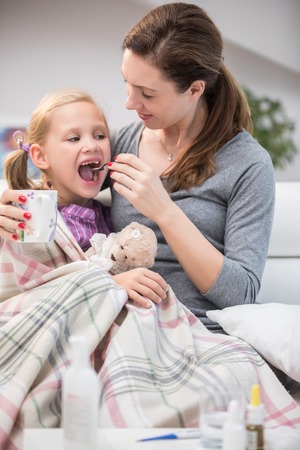 caring mother cures a young daughter for the disease at homeの写真素材