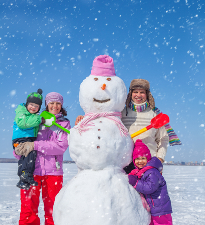 Happy couple with two children making big snowmanの写真素材