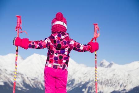 little girl on alpine skiing looks at the snow-capped mountainsの写真素材