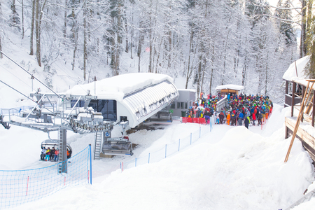 ong queue of people on the chairlift at the ski resort in the middle of the winter forestの写真素材