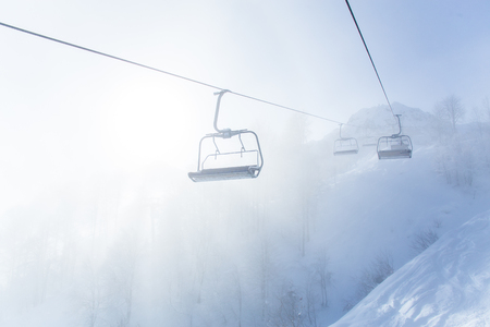 chairlift in a ski resort among snow-capped mountains in the fogの写真素材