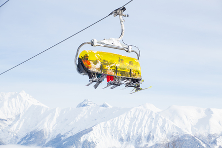 sports people on the chairlift in a ski resort among snow-capped mountainsの写真素材