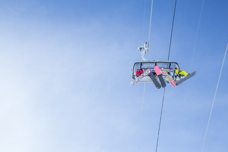 sports people on the chairlift in a ski resort among snow-capped mountainsの写真素材