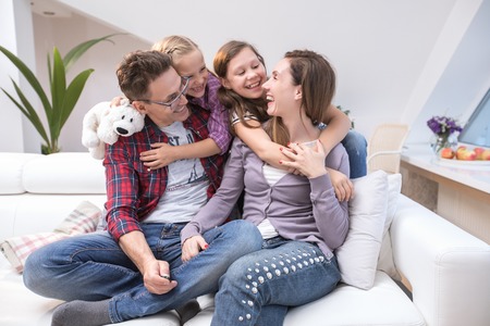 family lifestyle portrait of a mum and dad with their children having good time at homeの写真素材