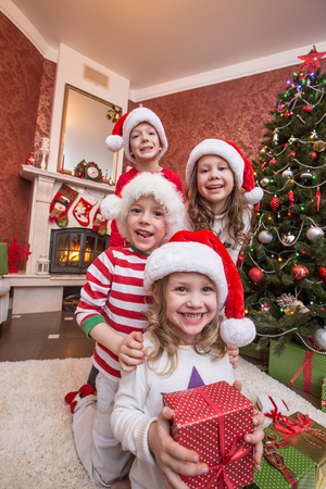 happy kids celebrating Christmas near the fireplace under the Christmas treeの写真素材