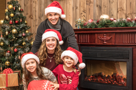 happy family celebrating Christmas near the fireplace under the Christmas treeの写真素材
